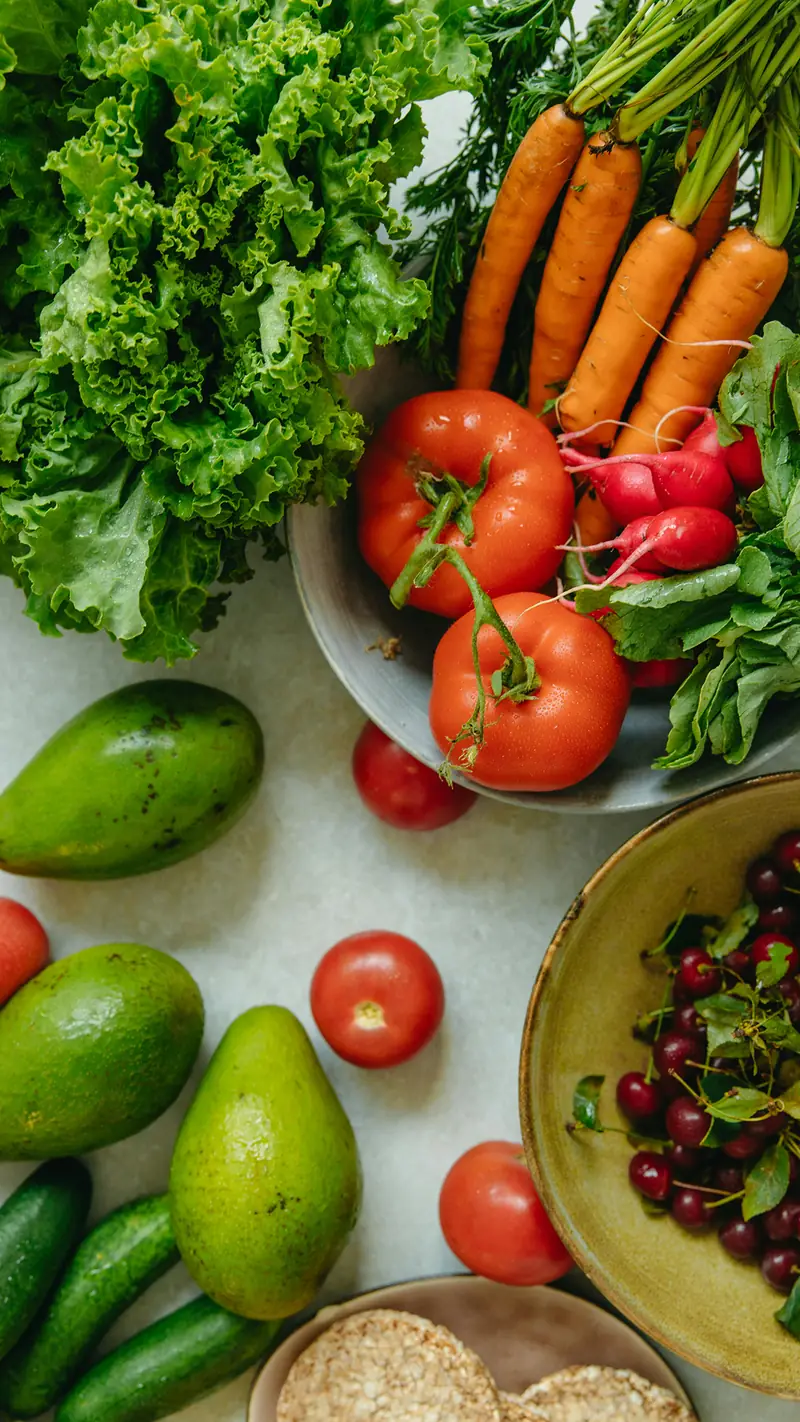 Tomates, avocats, carottes et radis frais disposés sur un plan de travail